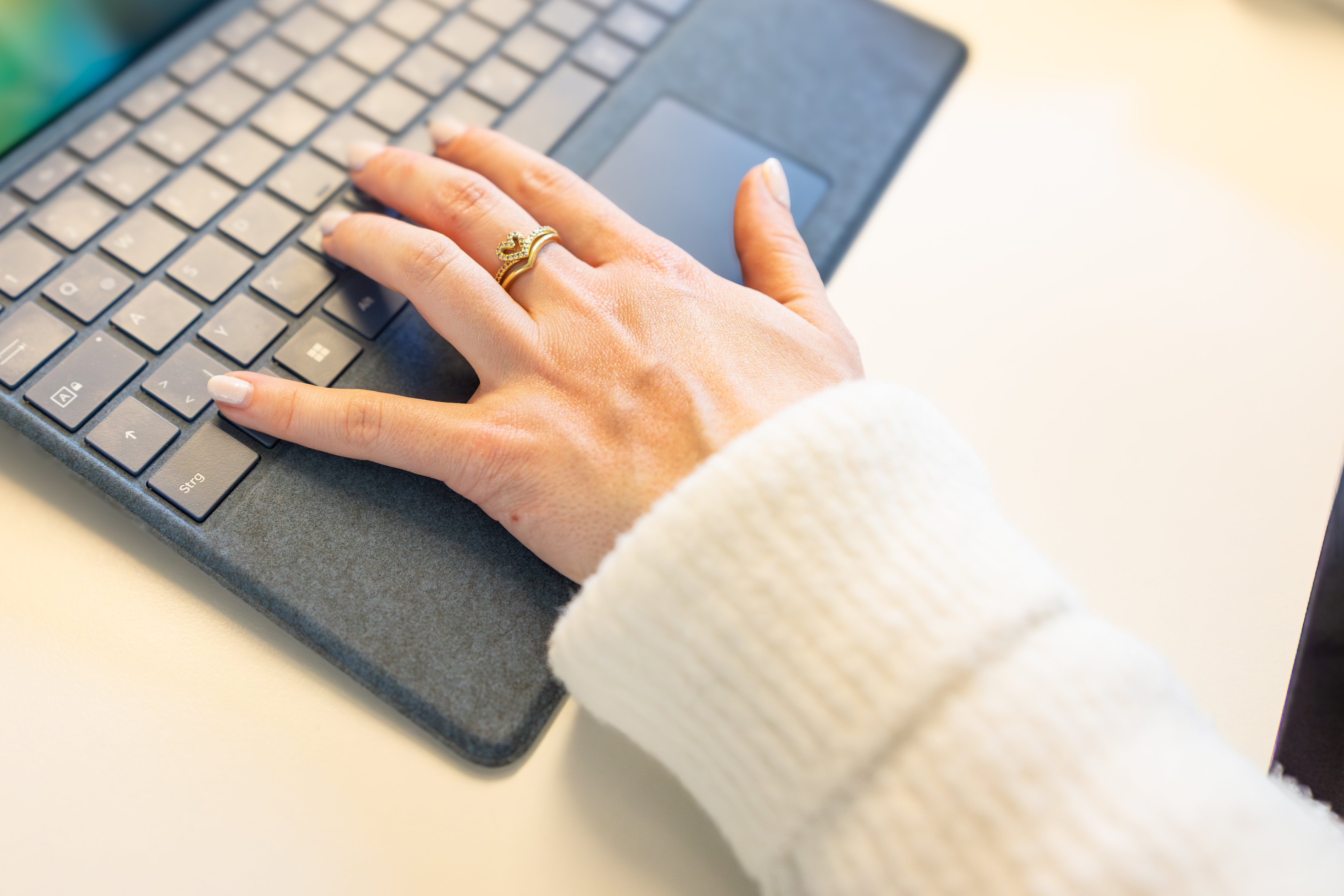 Eine Frau arbeitet am Laptop, zu sehen ist lediglich ihre Hand auf der Tastatur.  