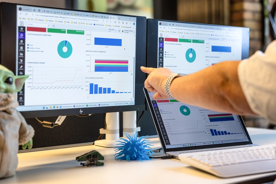 Mann zeigt mit dem Zeigefinger auf einen Bildschirm, auf dem Dashboards zu sehen sind.